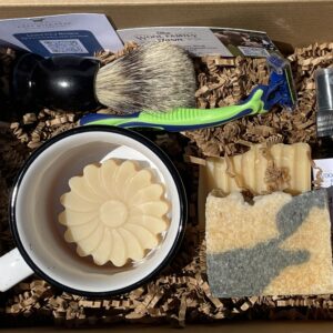 Men's shaving supplies: soap, mug, brush, razors, and aftershave oil.